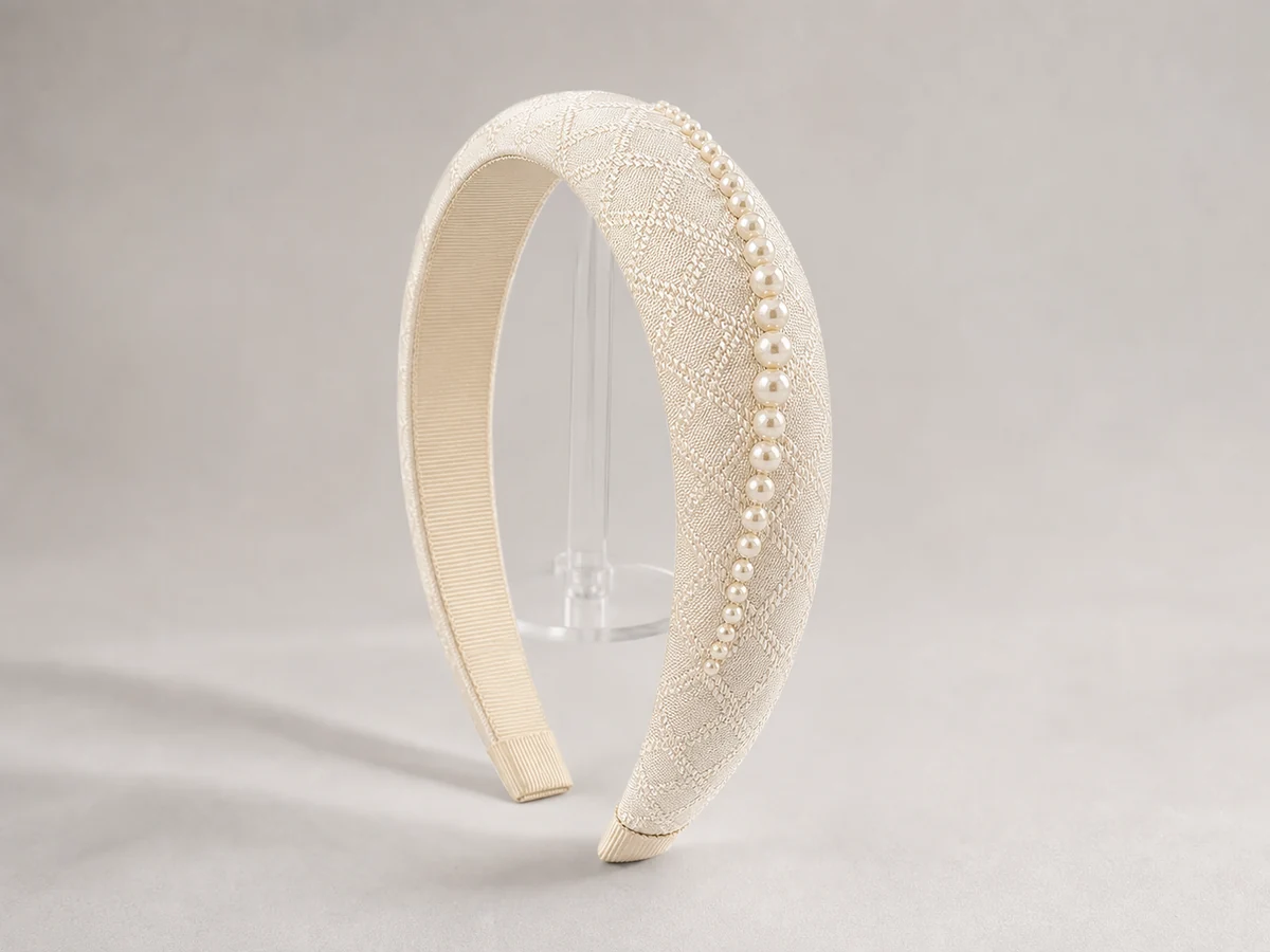 Warm ivory micro-jacquard padded headband with a graduated line of cream pearls